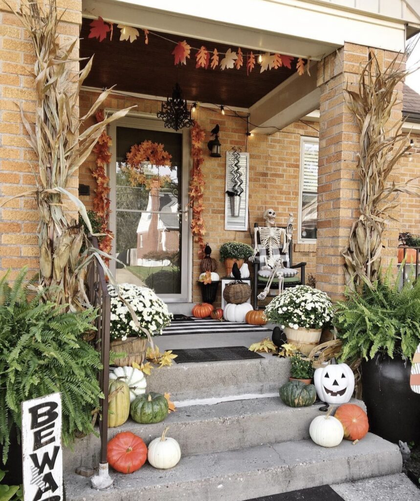 A skeleton with pumpkins and cornstalks.