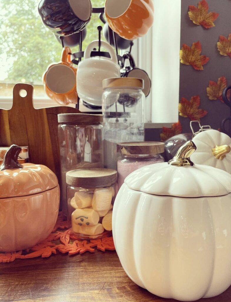 Pumpkin bowls with fall mugs and maple leaves on the wall.