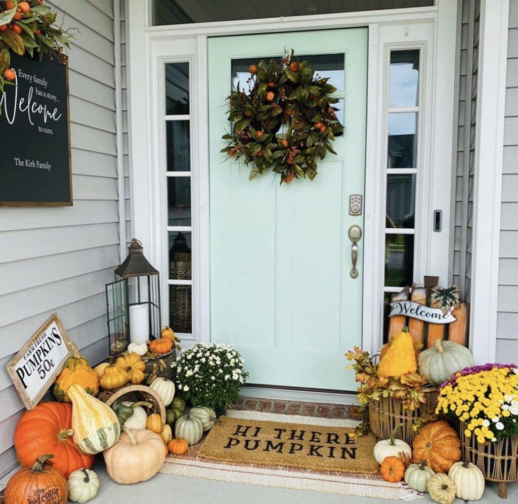 A blue door with a fall wreath and pumpkins.