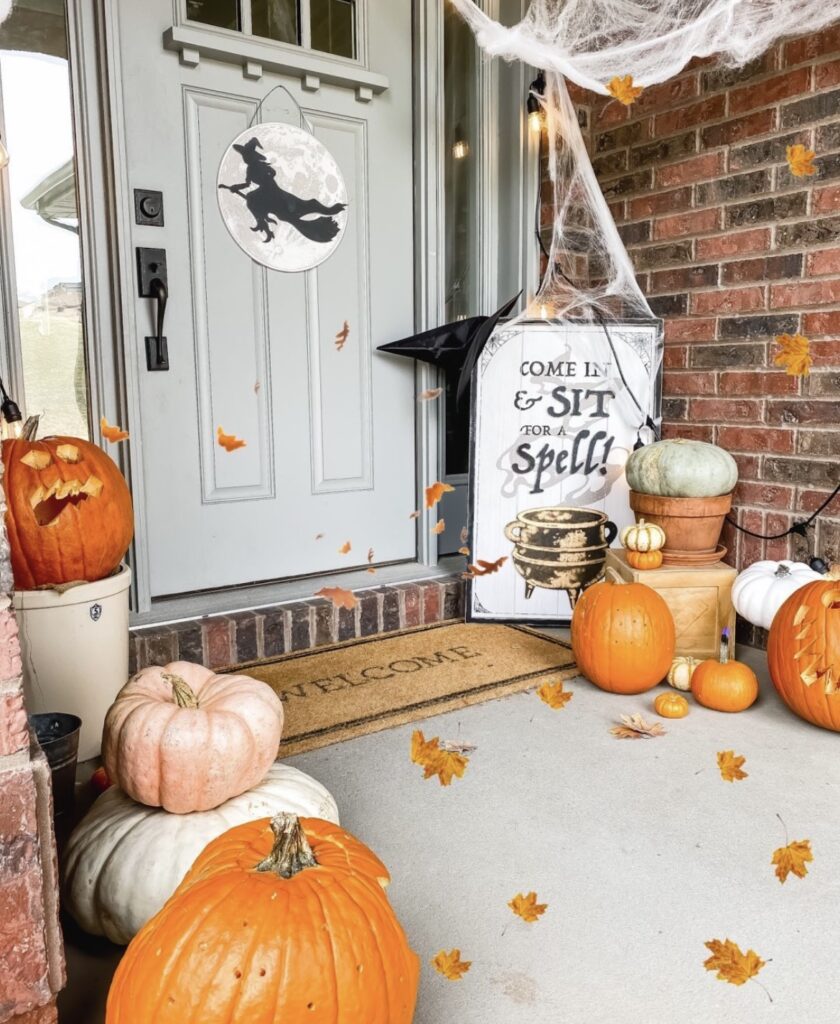 A witch door sign with pumpkins and spider web.