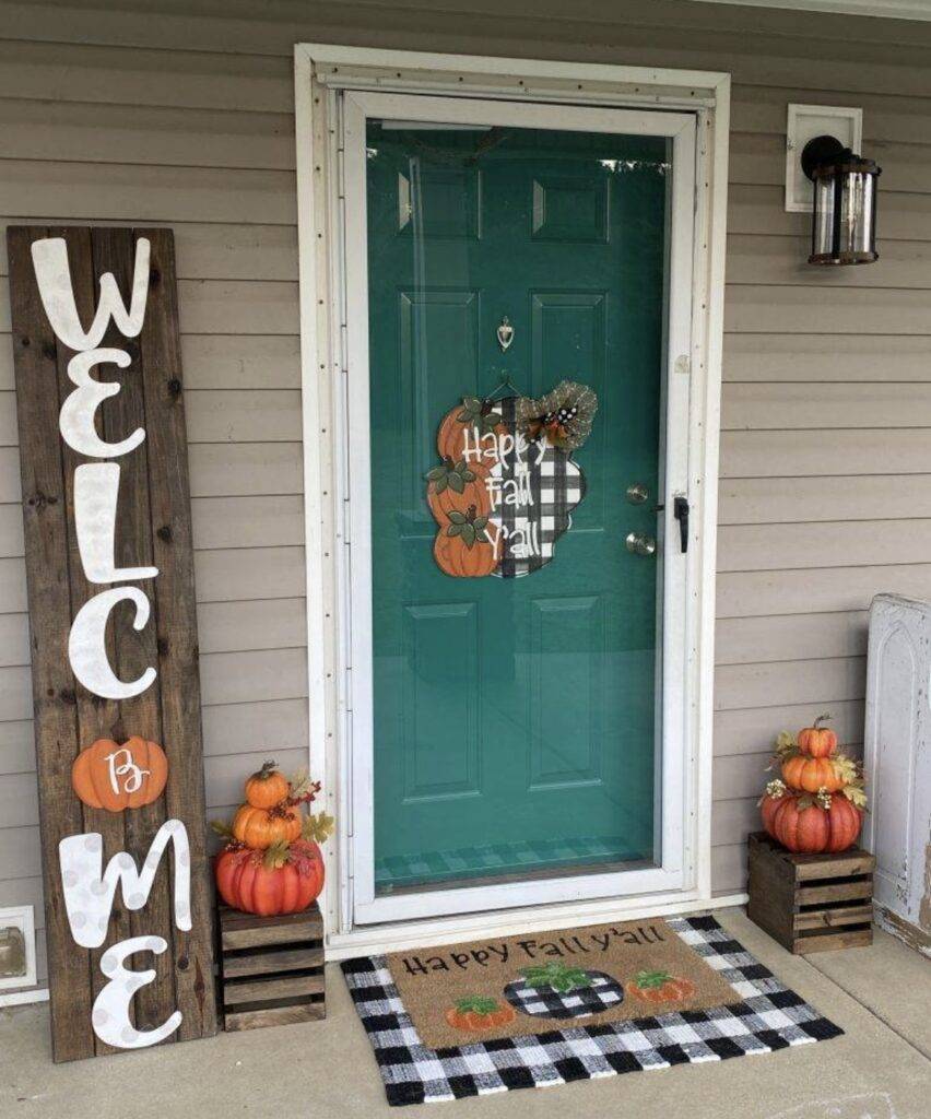 A blue door with a welcome sign and pumpkins.