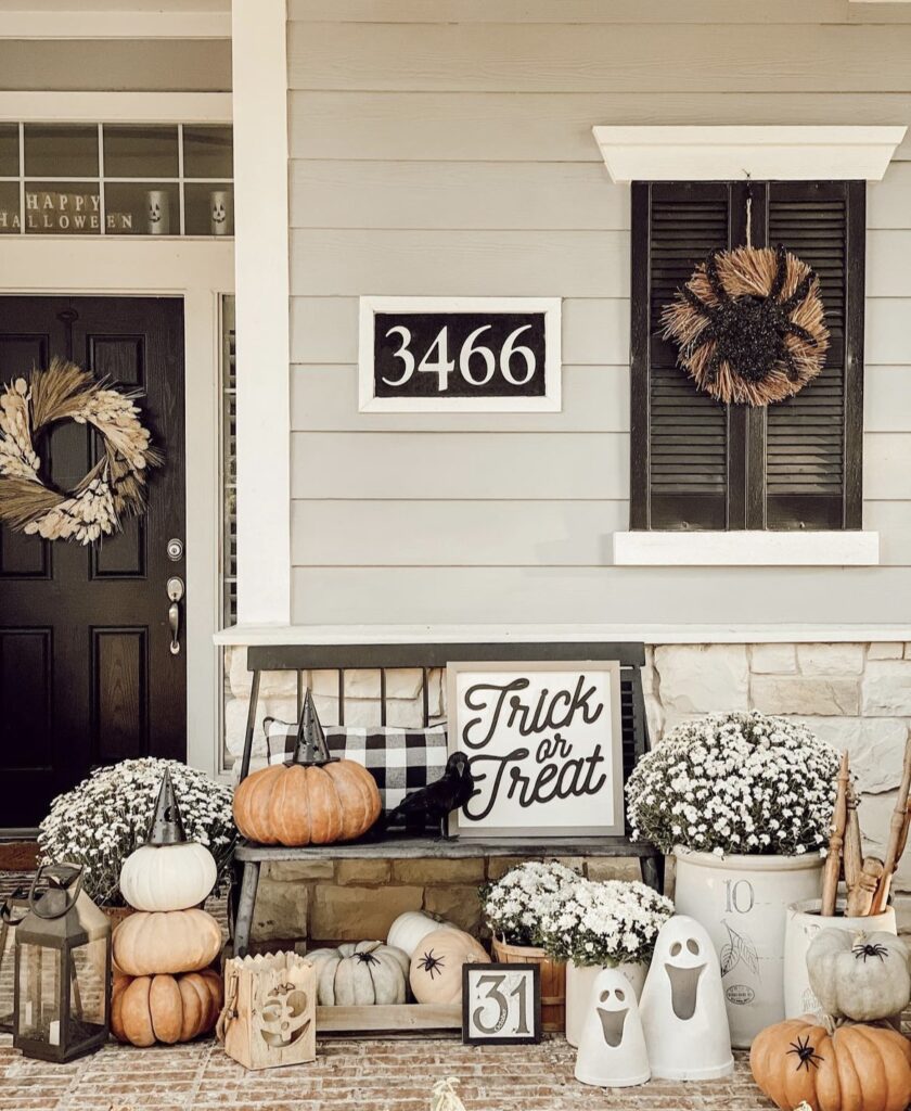 Crows, pumpkins, chrysanthemums and pillows on a porch.