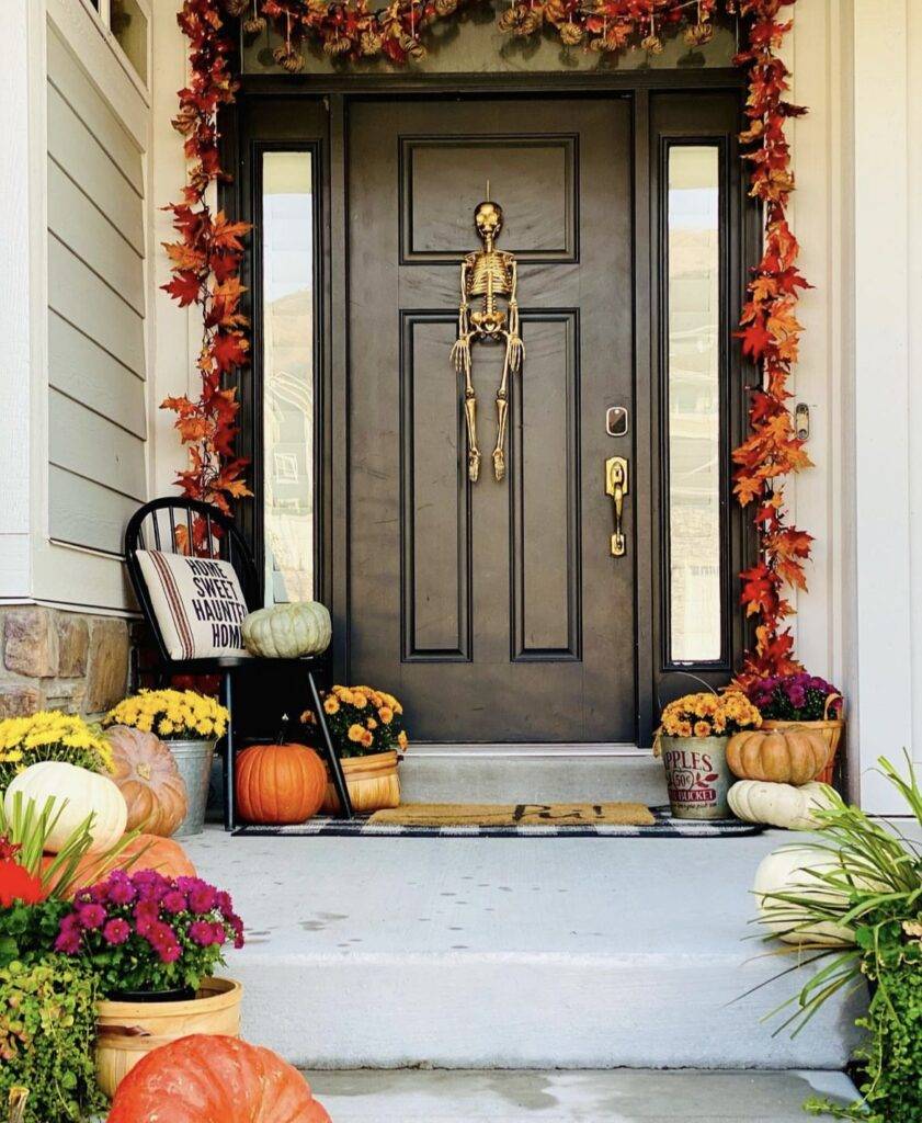 A maple leaf garland with a gold skeleton and pumpkins.