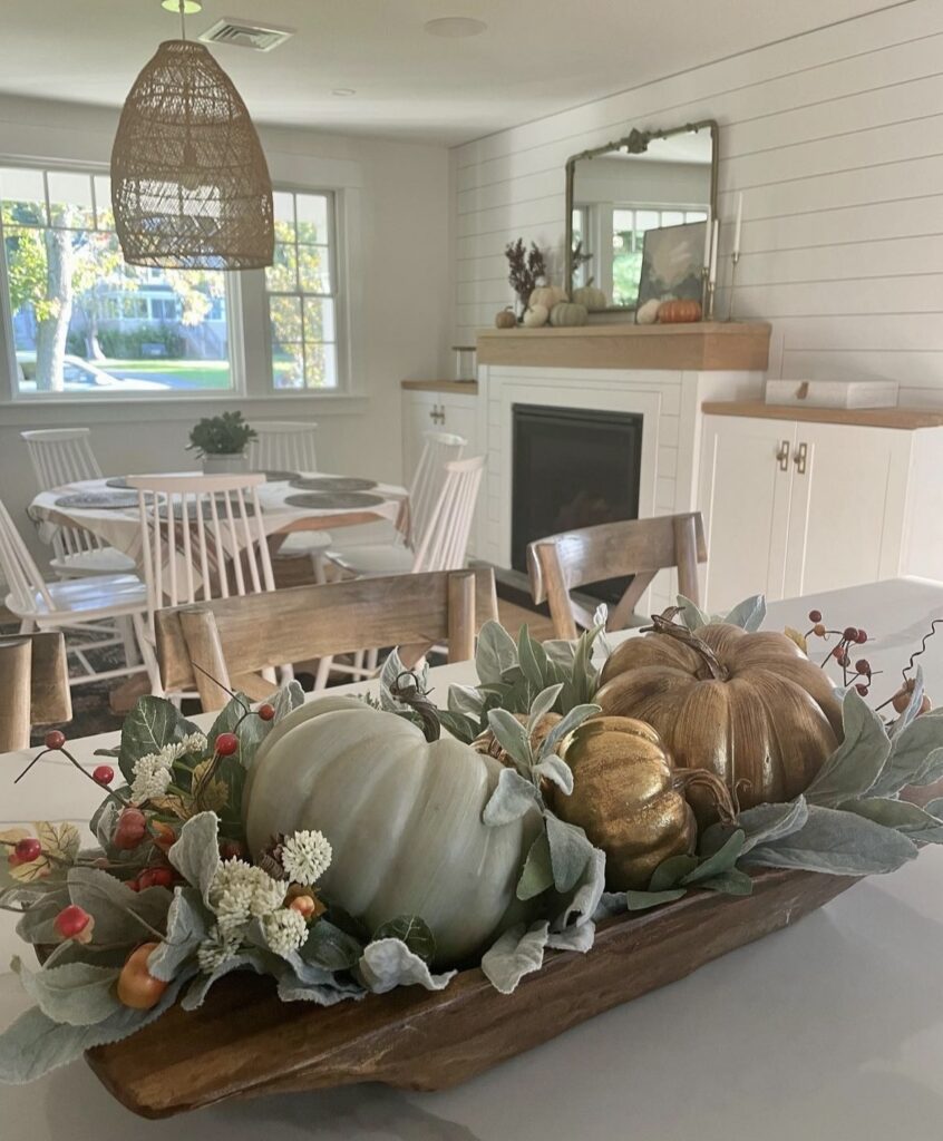 A fall centerpiece with eucalyptus leaves, pumpkins and berries.