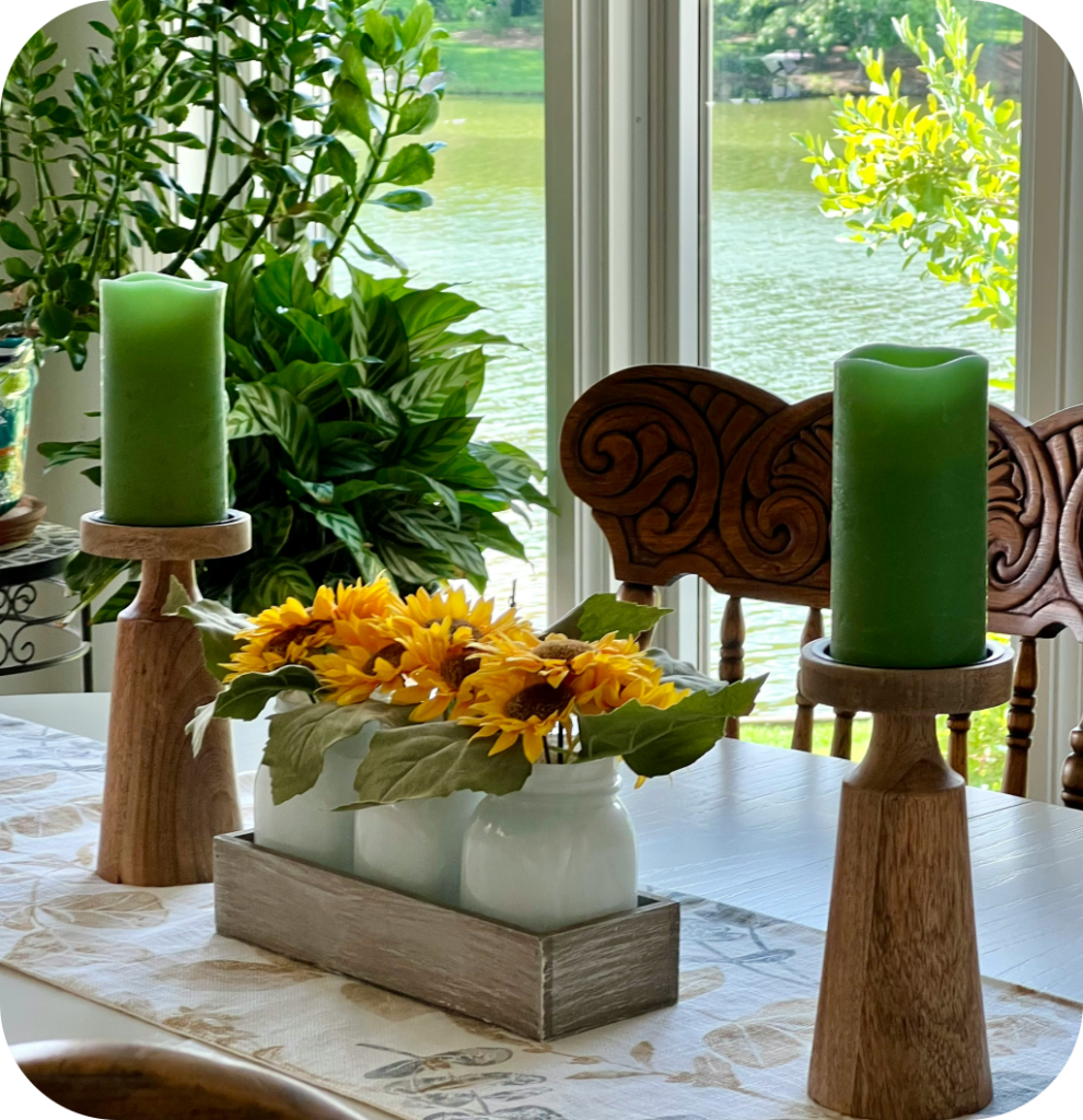 A summer centerpiece with sunflowers, green candles and wooden candle holders.