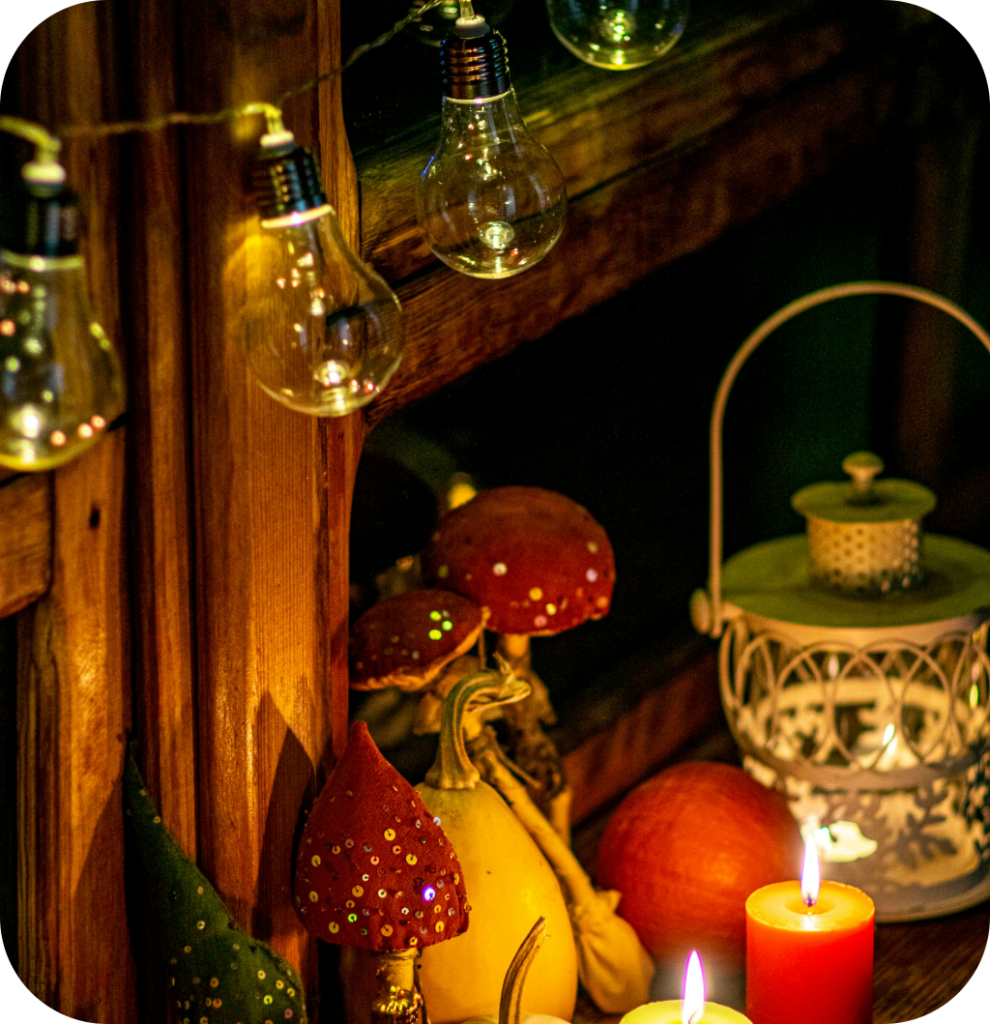 A lantern with lighted candles, mushroom figurines and pumpkins.