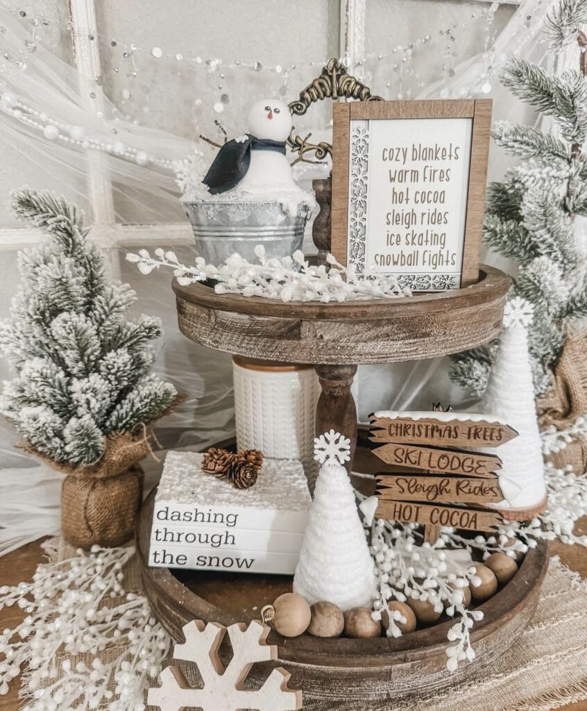 A wooden tray filled with snowman and white Christmas decorations.