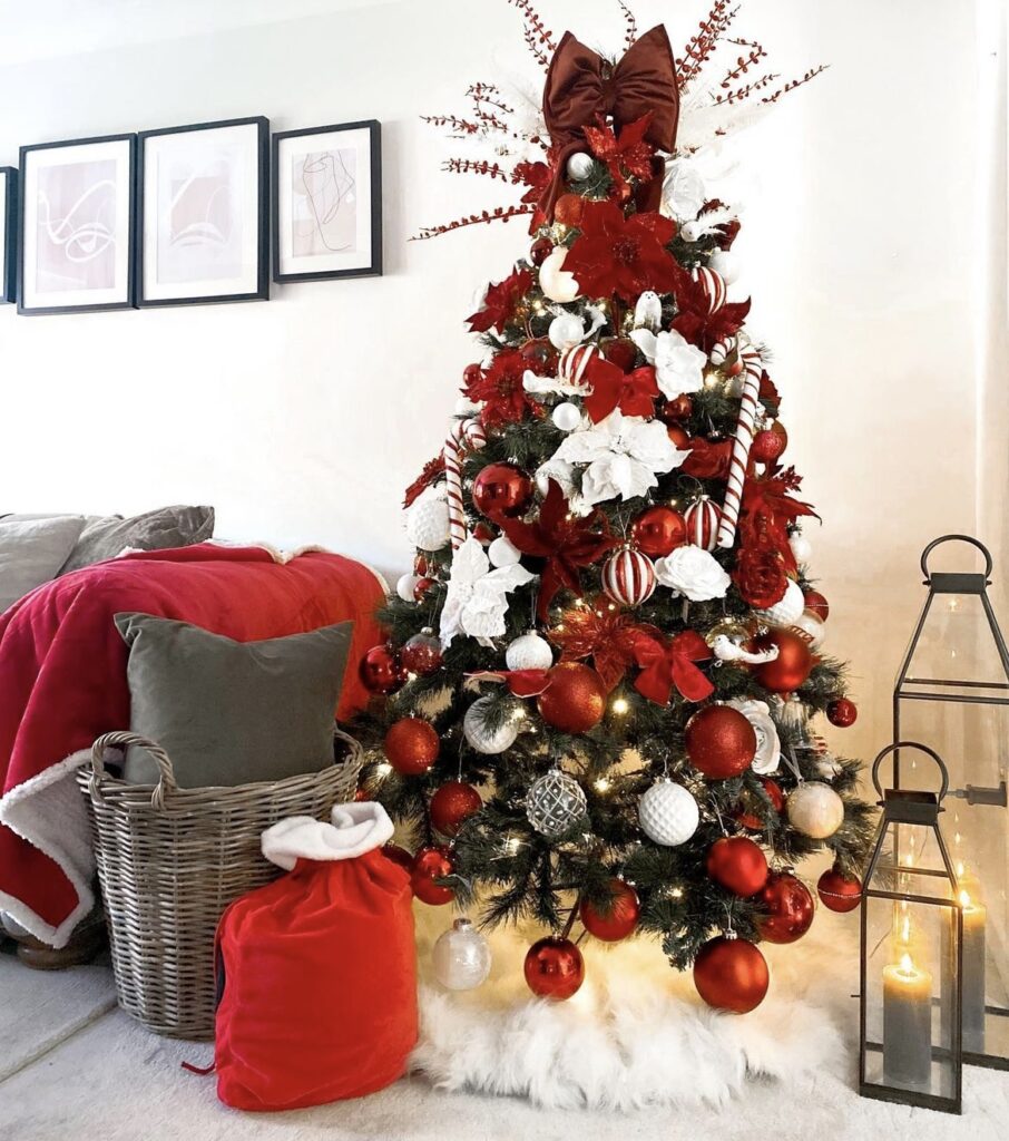 A red Christmas tree with ribbon bows and poinsettias.