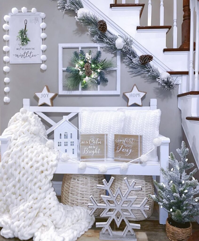 A white bench with a white blanket and a white pom pom garland.