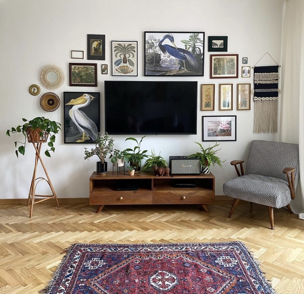 A gallery wall filled with tropical animal and forest paintings around the TV.