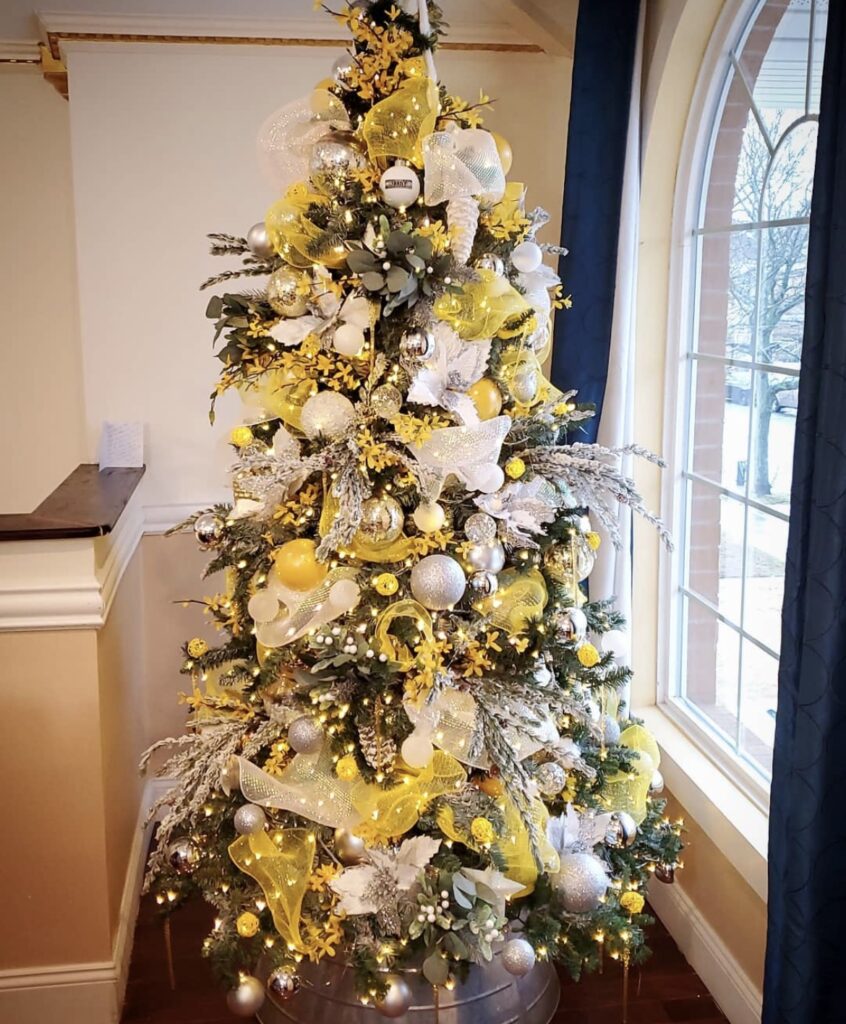 A yellow Christmas tree with yellow flowers and white berries.