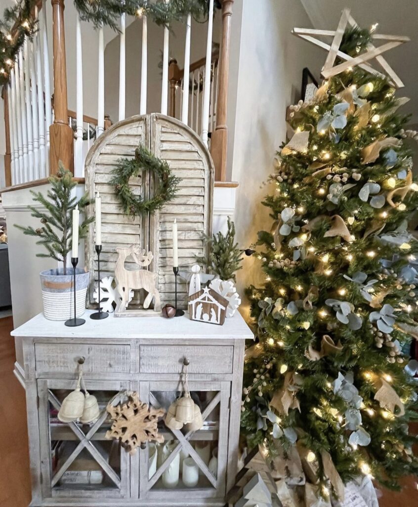 A farmhouse decoration with wooden deer and wooden cutouts next to a Christmas tree.