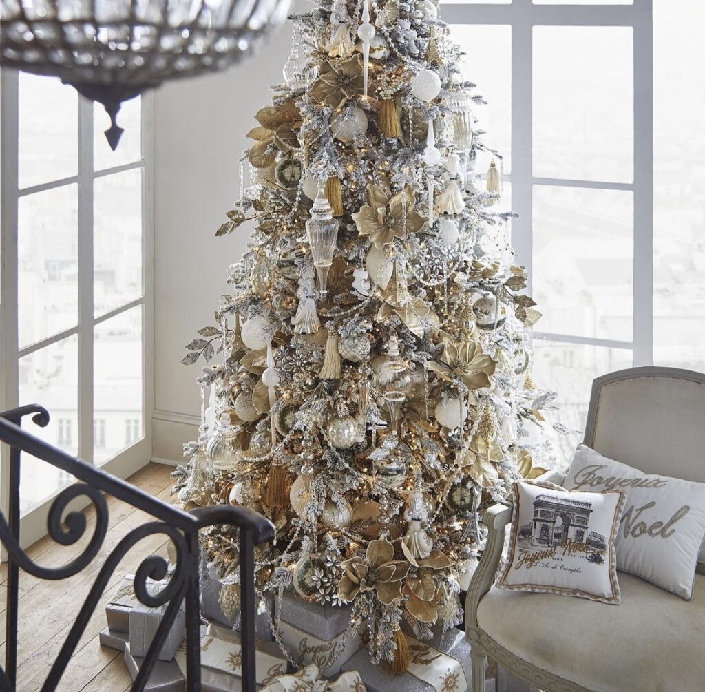 A gold Christmas tree with Santa Claus figurines and flowers.