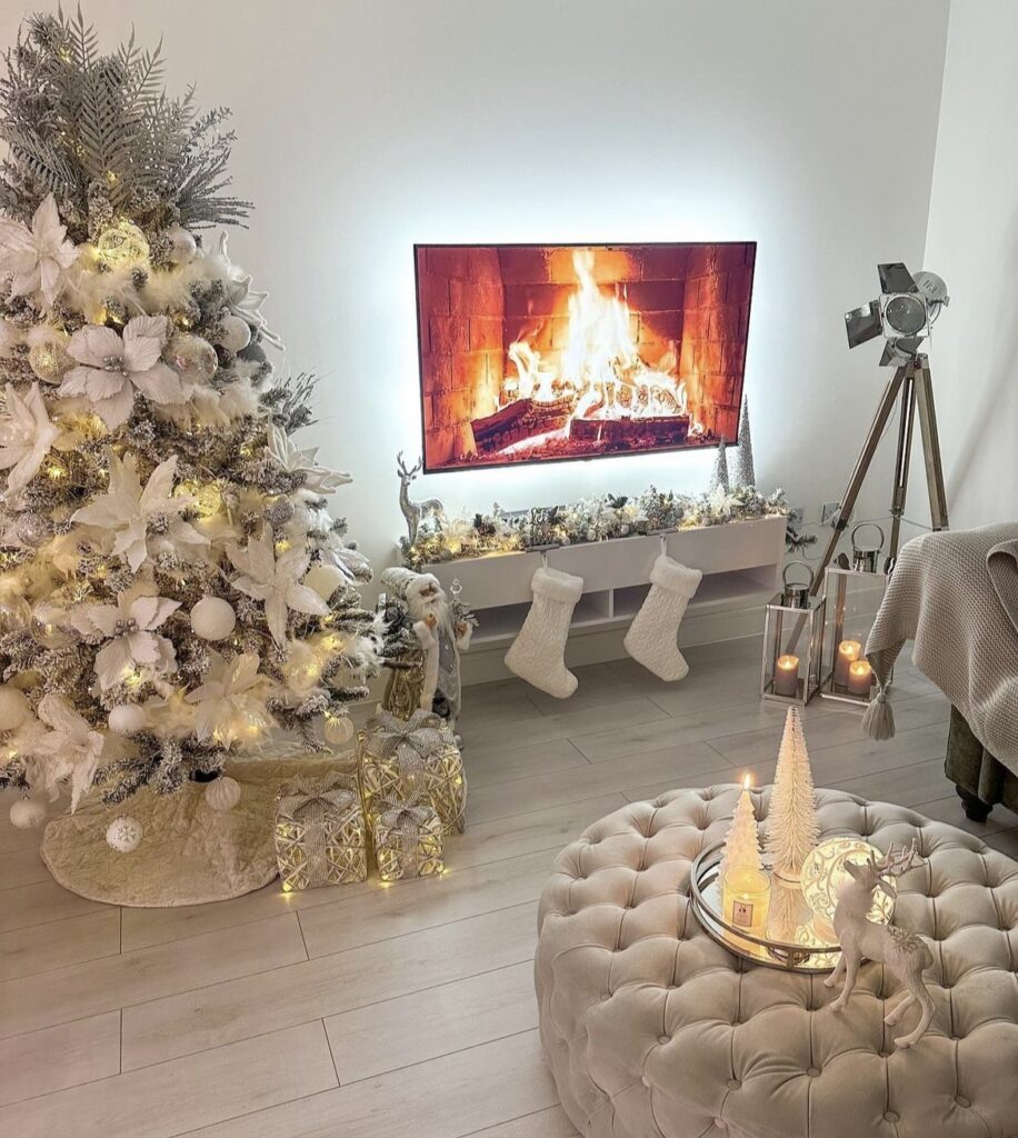 A white Christmas tree next to white reindeer and Christmas stockings.