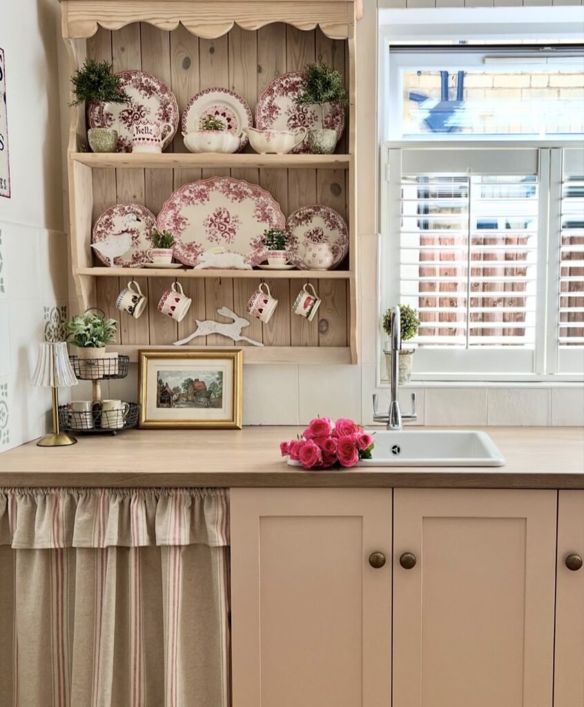 A shabby chic kitchen with pink plates and a wooden kitchen cabinet.