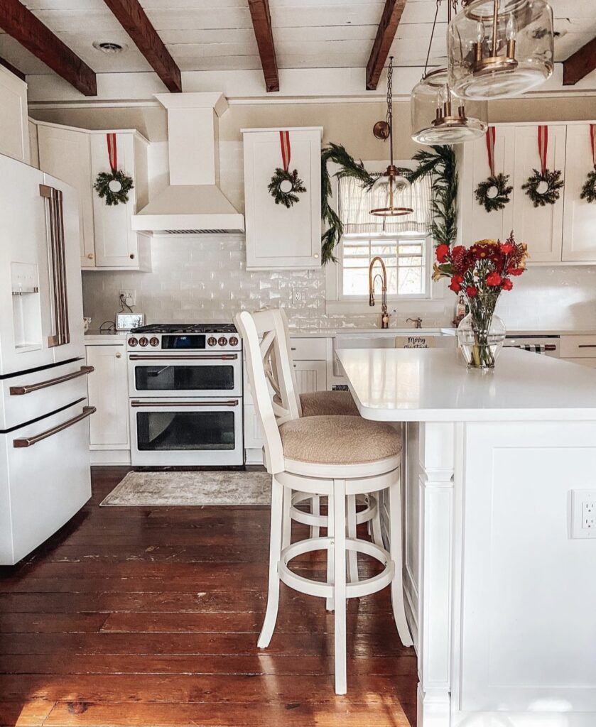 Wreaths with red ribbons hanging on kitchen cabinet doors.