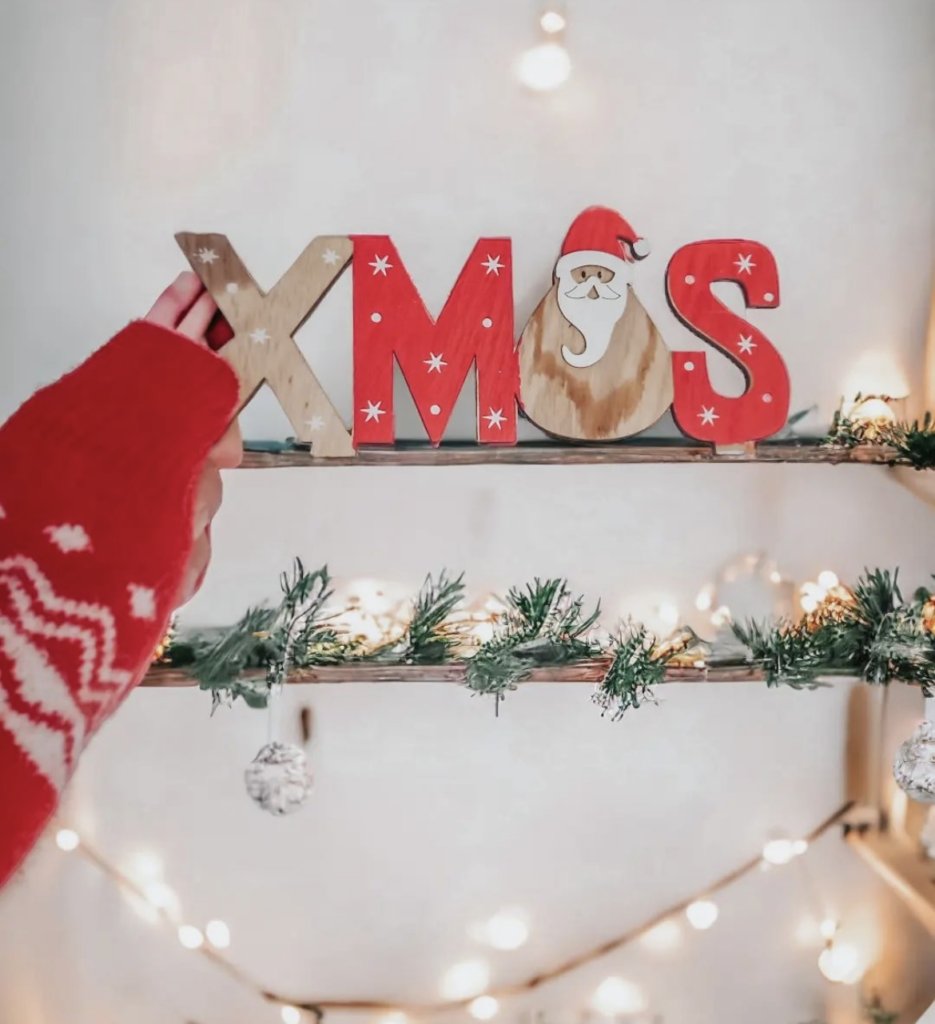 A christmas wooden sign on a shelf.