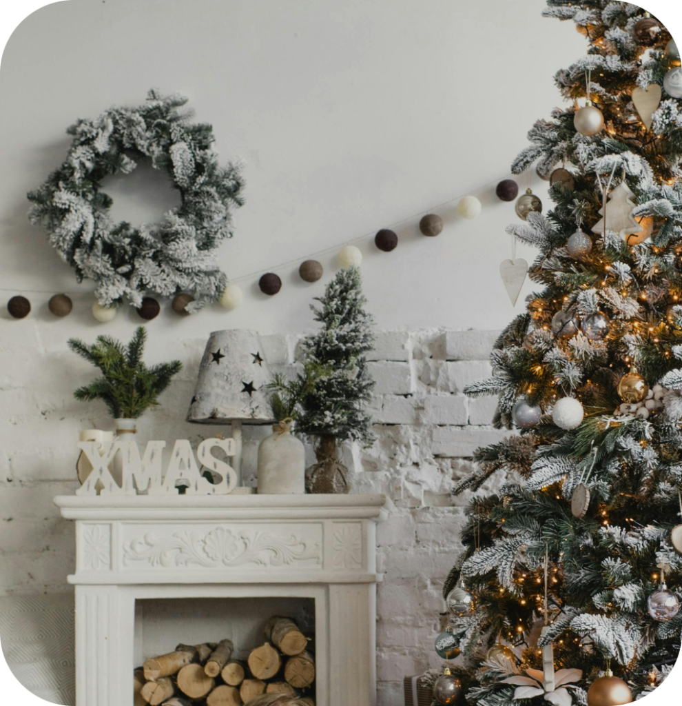 A white mantel with a "Xmas" wooden sign next to a Christmas tree.