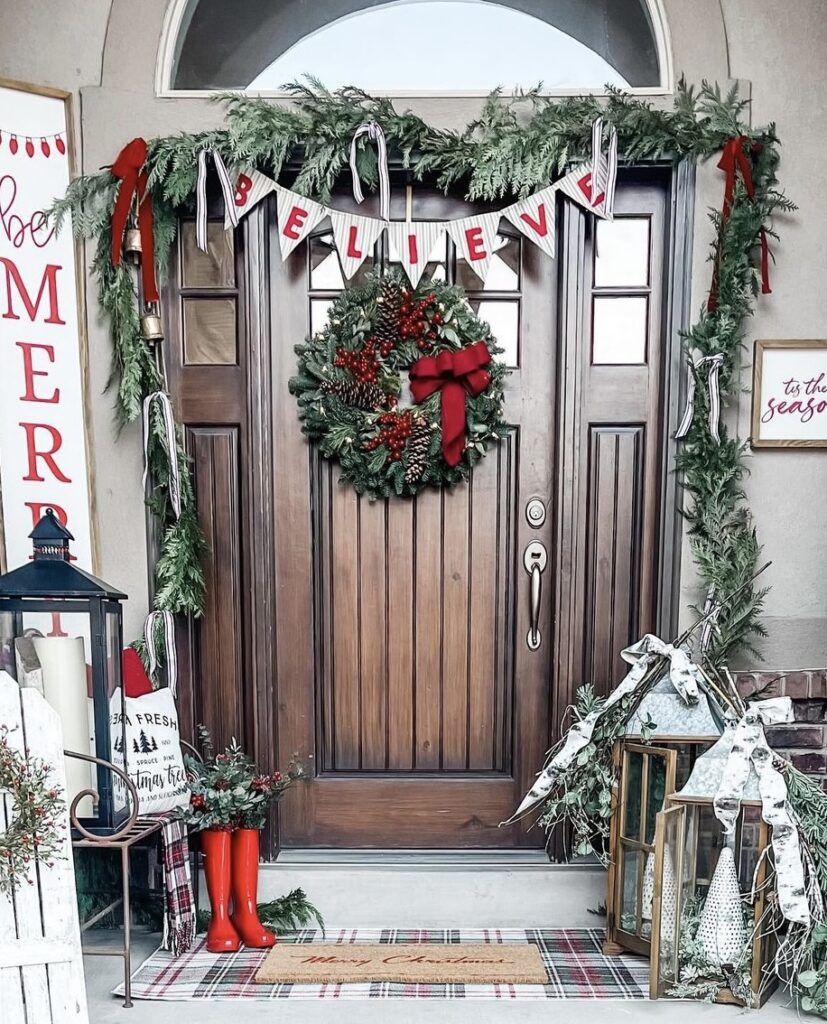 A Christmas porch with a "believe" banner and candle lanterns.