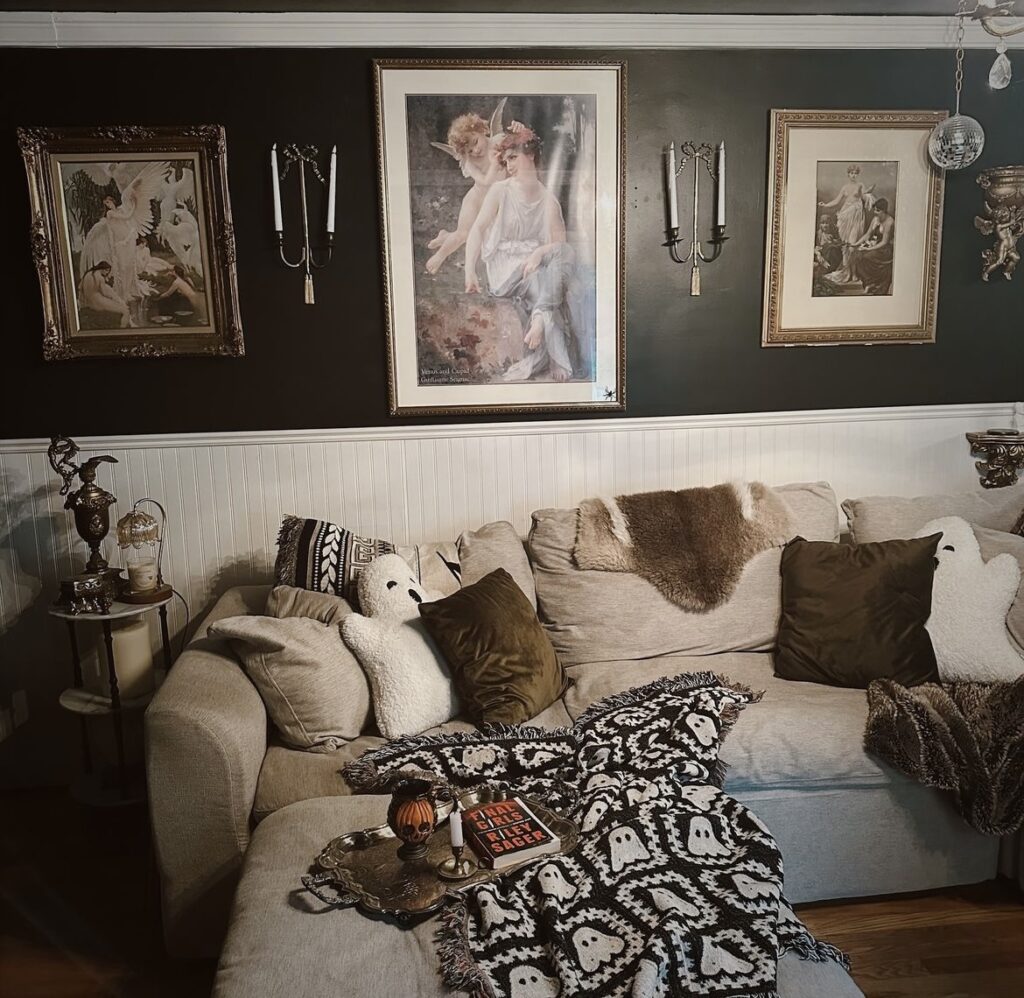 A cozy living room with a black accent wall and antique paintings.