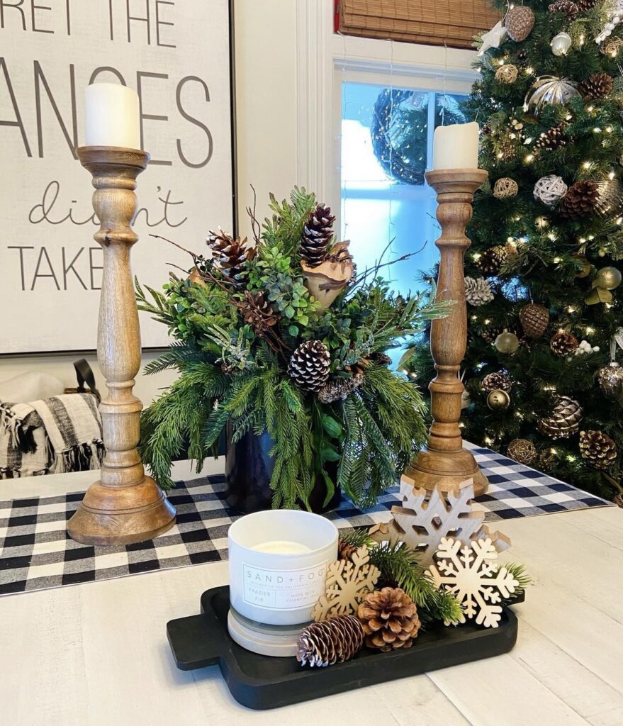 A Christmas centerpiece with wooden candle holders and pine branches.