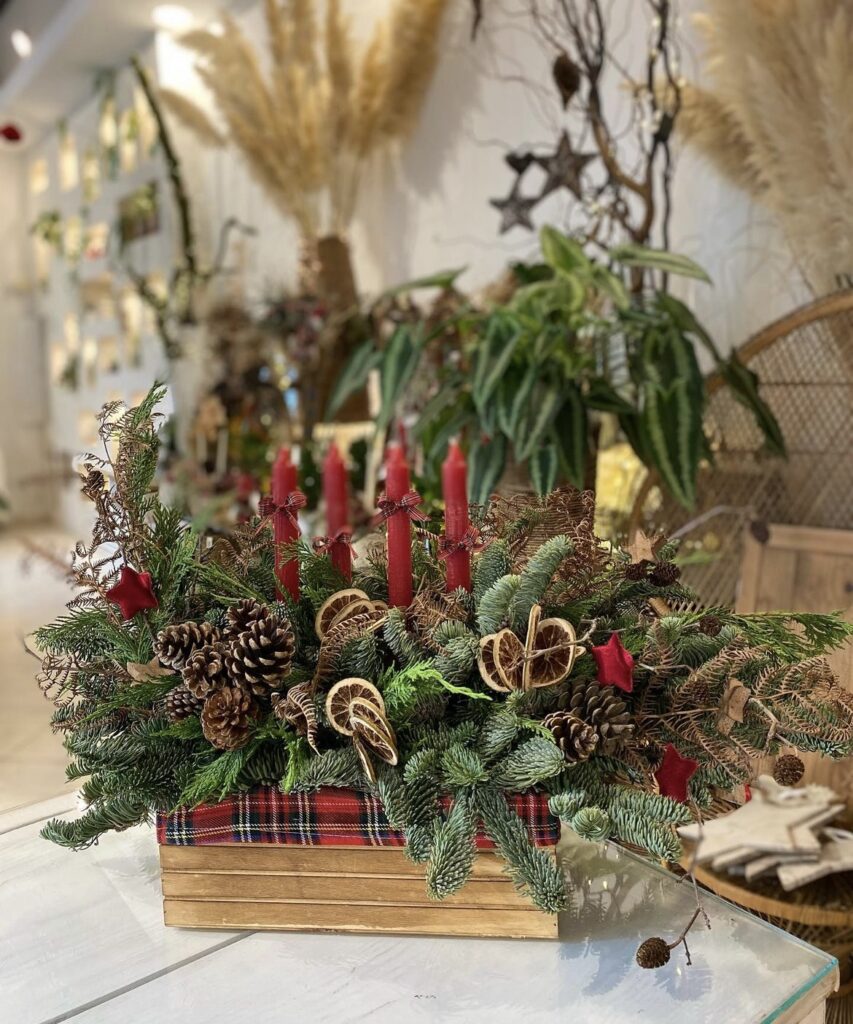 A Christmas centerpiece with red taper candles and tartan ribbon.