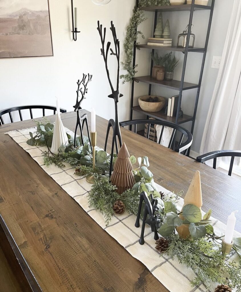 A Christmas centerpiece with black reindeer and mini pine trees.