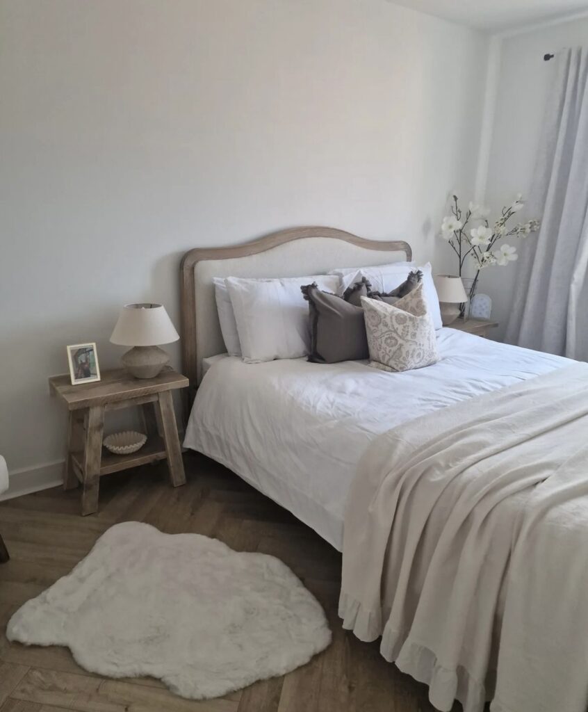 A farmhouse bedroom with a wooden nightstand table and headboard.