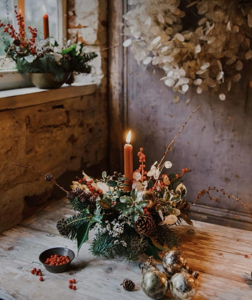 A Christmas centerpiece with red candles and pine branches.