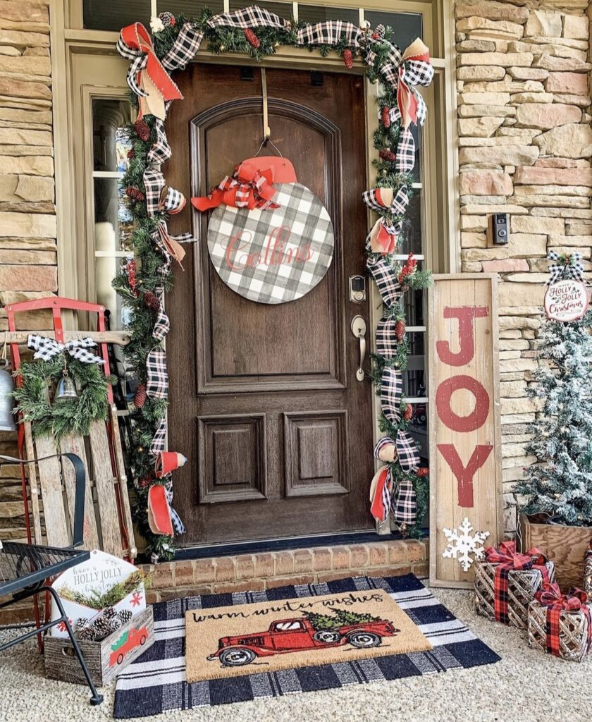 A Christmas porch with black and white buffalo plaid ribbon and red ribbon bows.