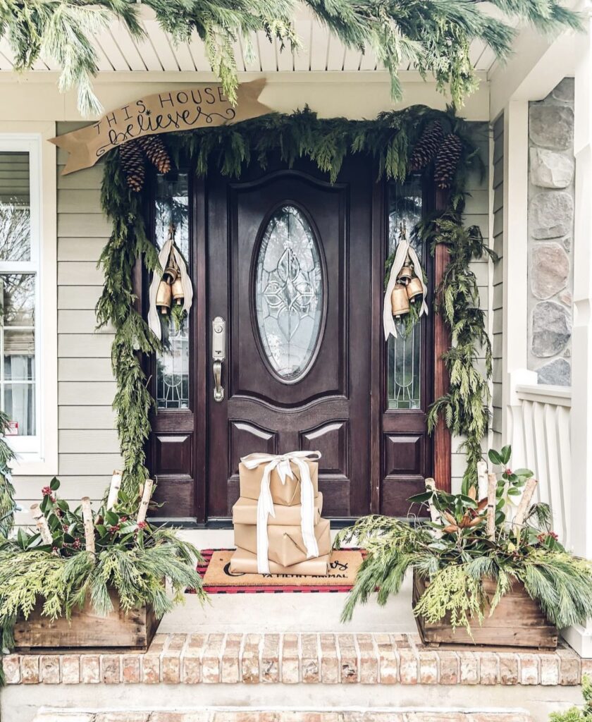 A Christmas porch with pine branches and rustic cow bells.