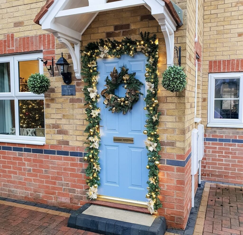 A pine branch garland with string lights, gold and cream ornaments.