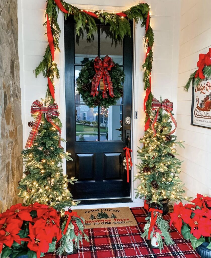 A Christmas porch with string lights and red poinsettias.