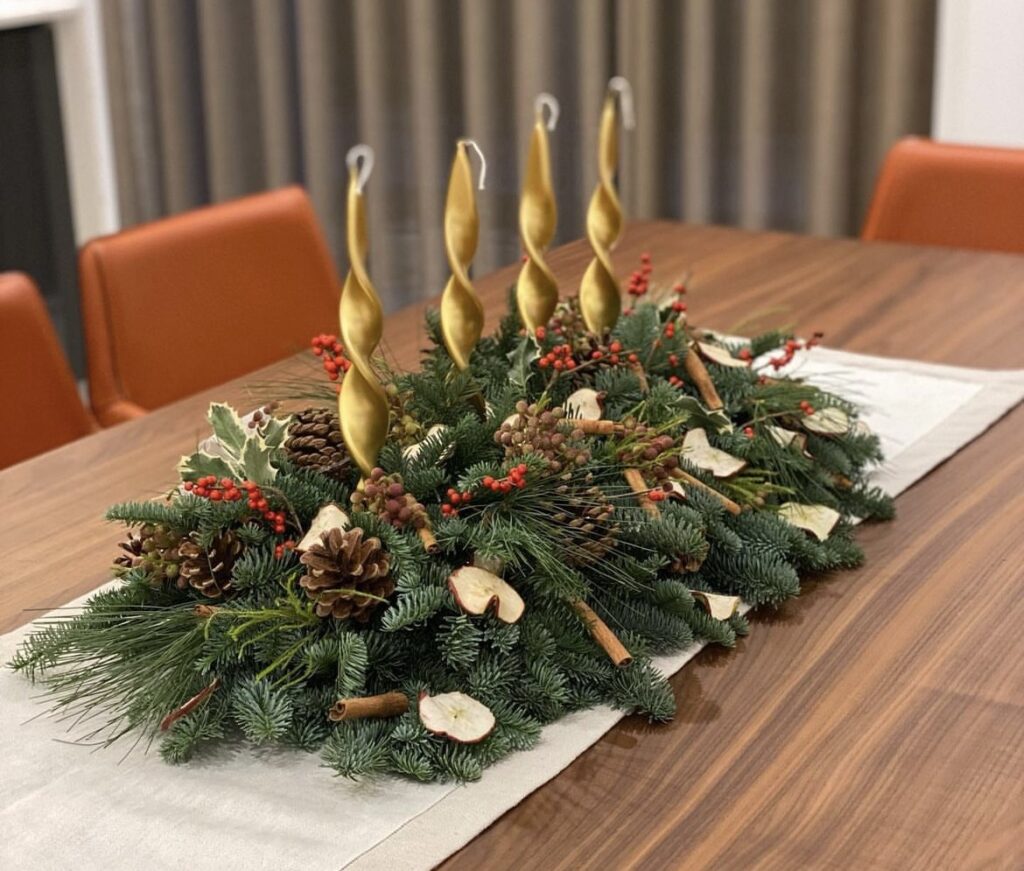 A Christmas centerpiece with twistet gold candles and pine branches.