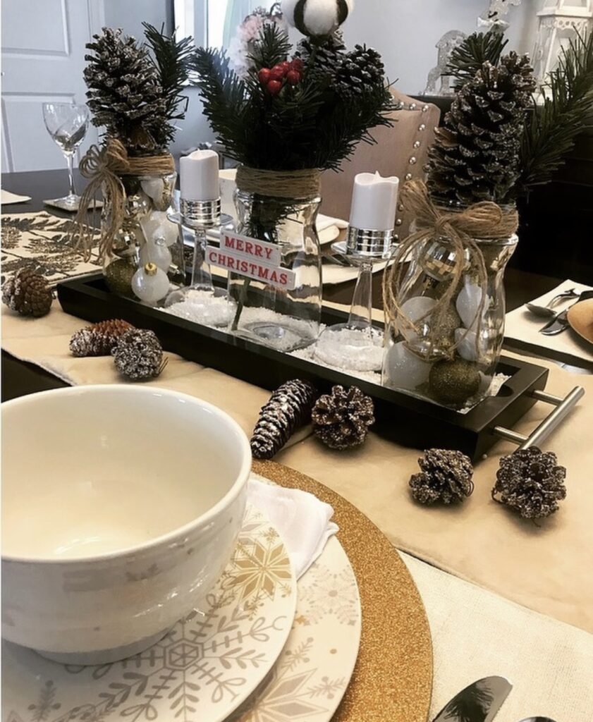 A Christmas centerpiece with mason jars and pine branches.