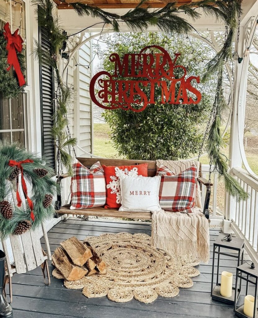 A Christmas porch with a "Merry Christmas" wooden sign above a swing.