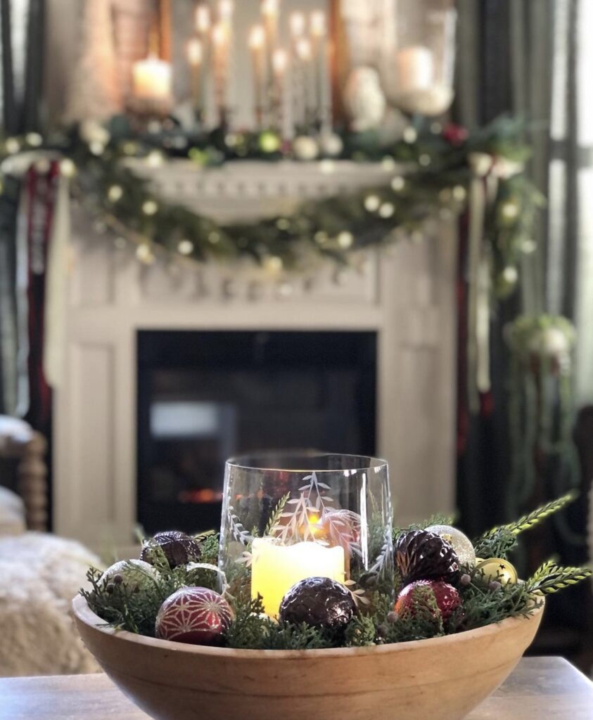 A white candle with pine branches and Christmas balls.