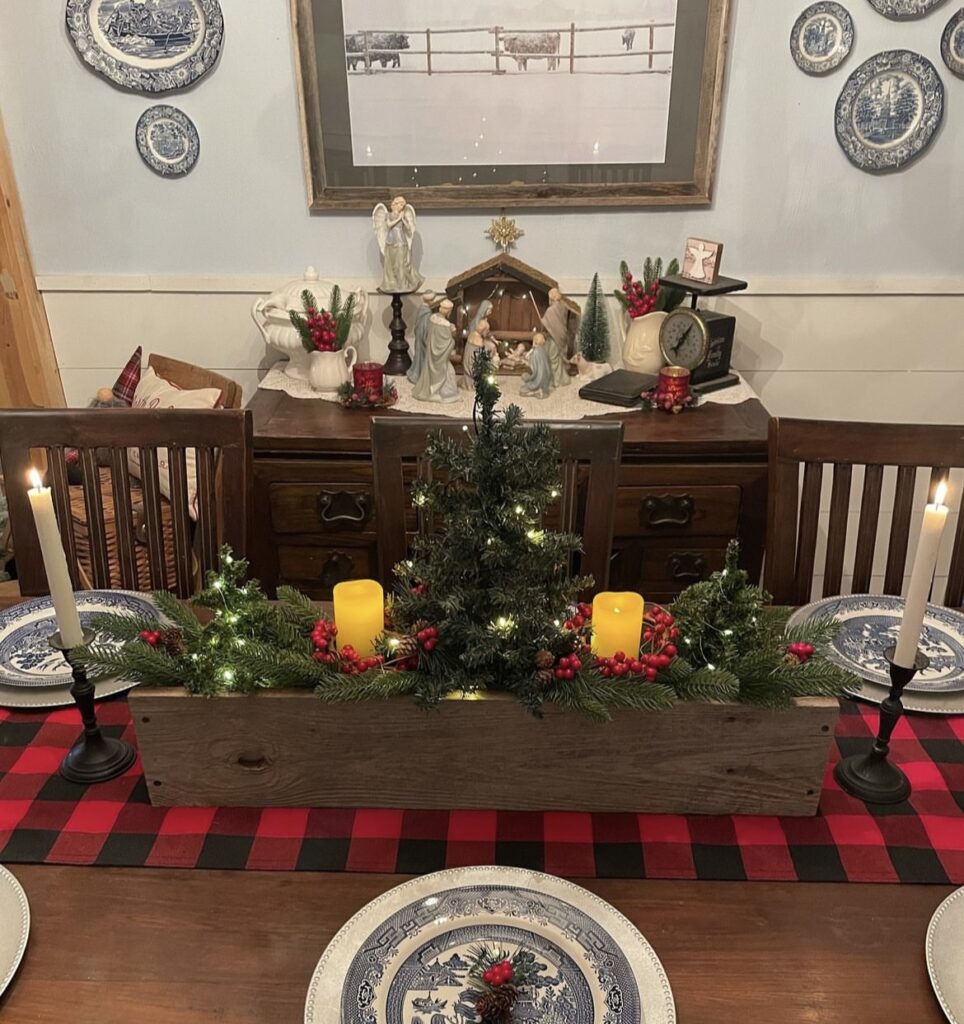 A Christmas centerpiece with mini pine trees and yellow candles.