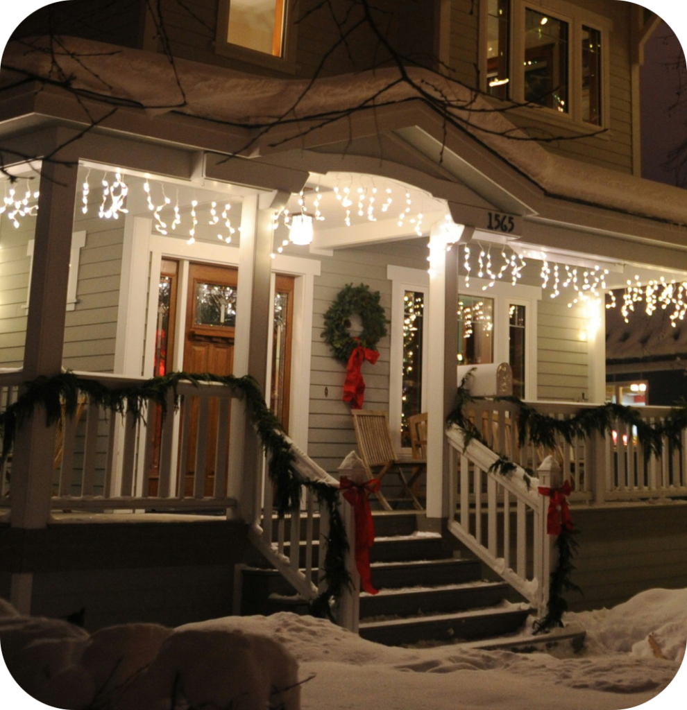 A Christmas porch with string lights and a Christmas wreath.