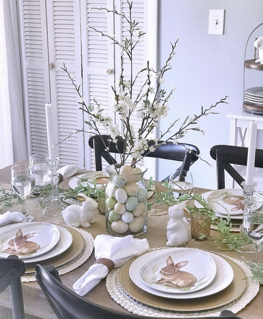 A glass vase with Easter eggs and cherry blossom branches.