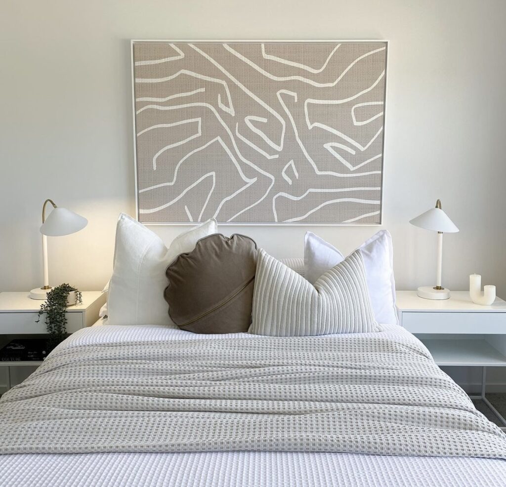 A neutral bedroom with modern artworks.