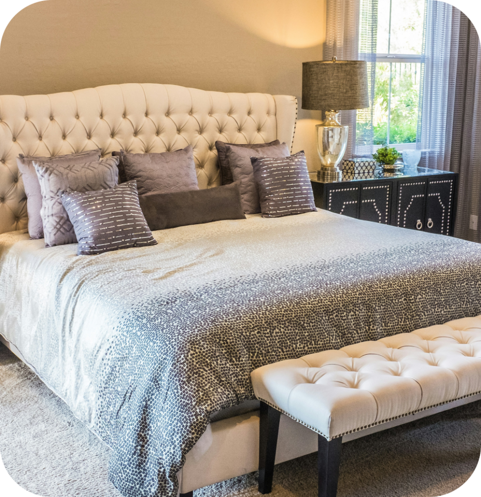 A neutral bedroom with a quilted bench.