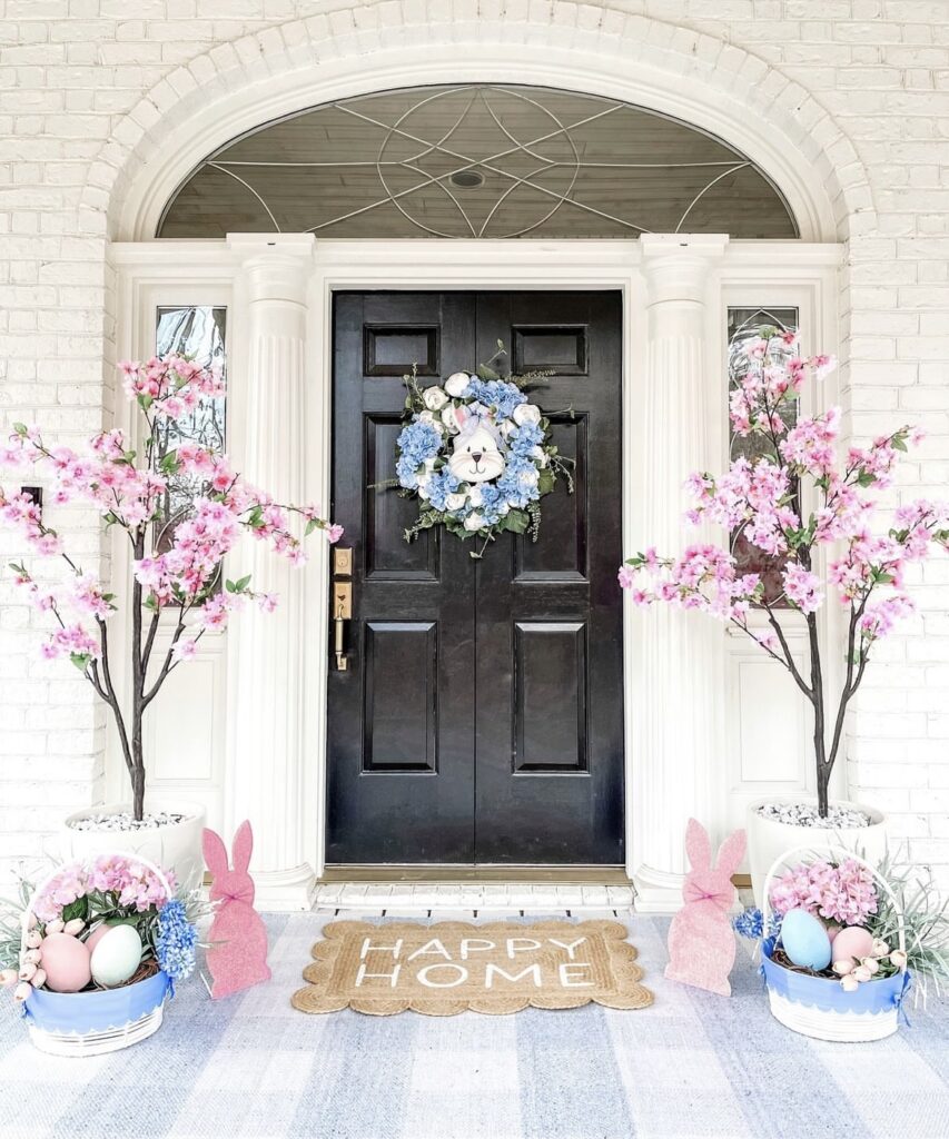 A blue and white wreath with a rabbit cutout on a black front door.