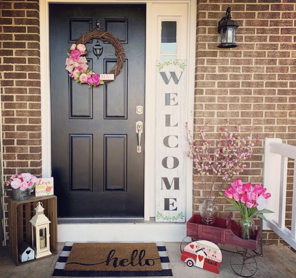 A front porch with a Valentine wreath and candle lantern.