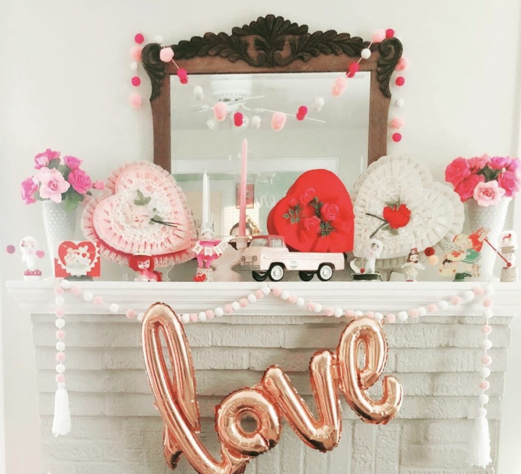 A mantel with a love balloon and Valentine paper fans.