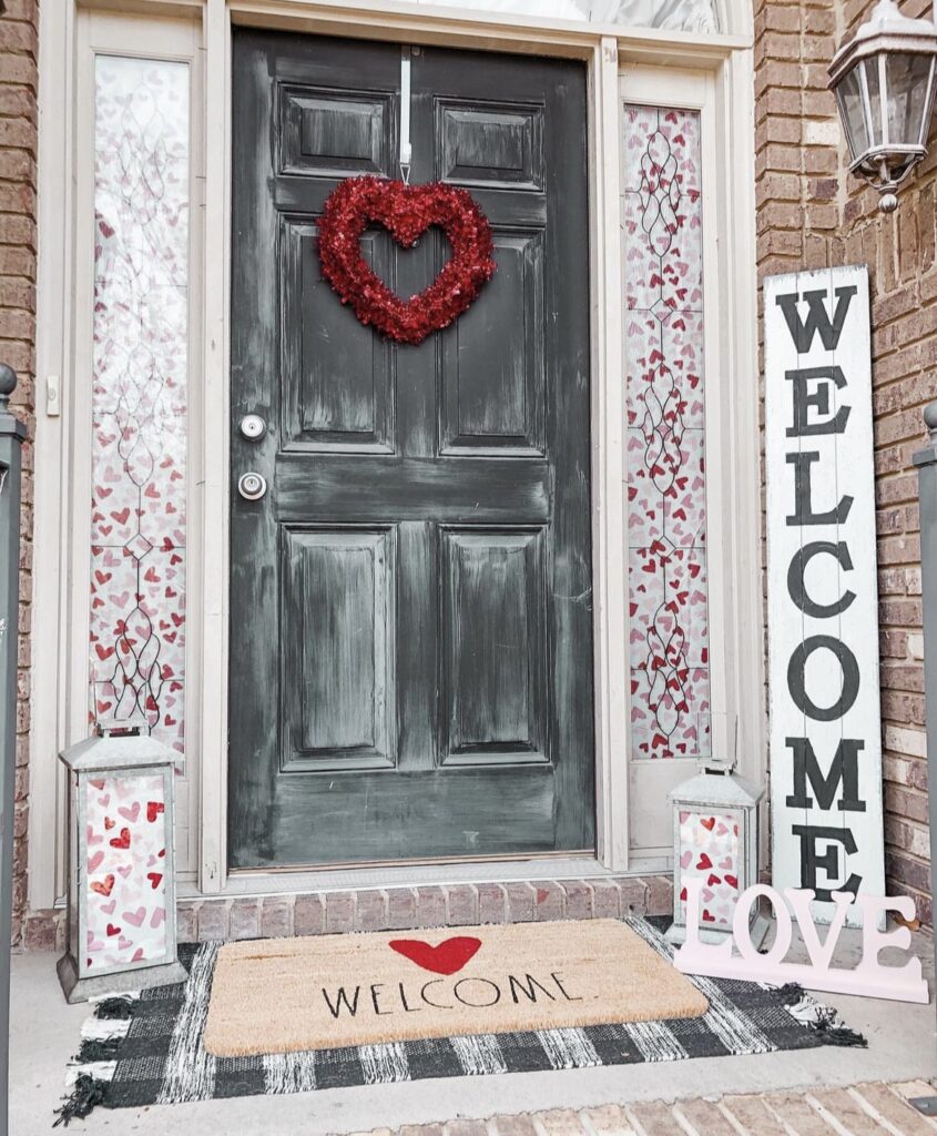 A front porch with a Valentine mat and welcome sign.