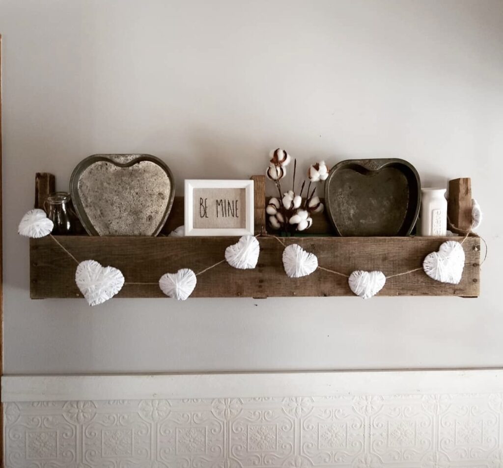 A shelf with heart shaped pans and a heart garland.