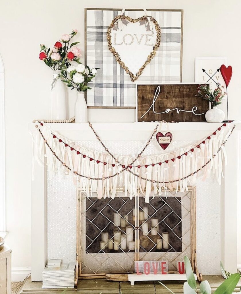 A mantel with Valentine garlands and a love sign.