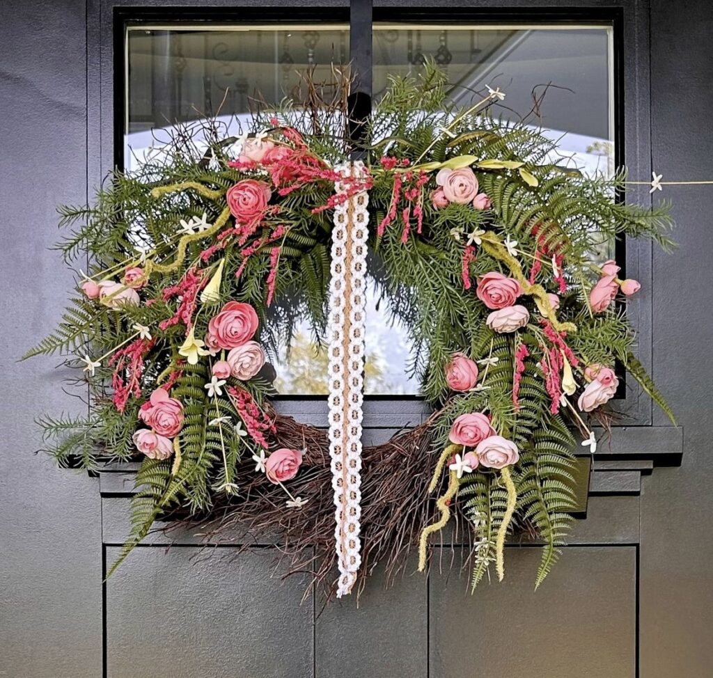 A wreath with greenery and pink flowers.