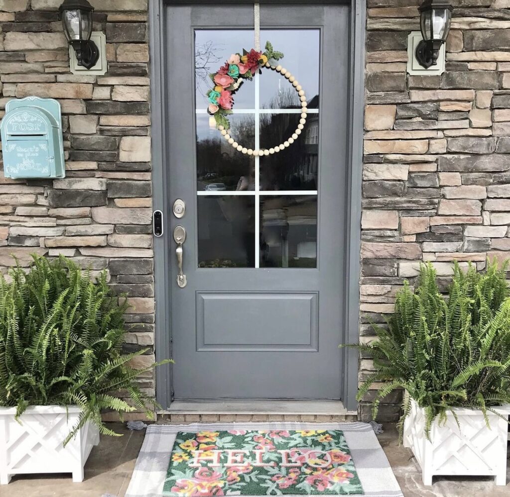 A wooden bead wreath on a gray front door.